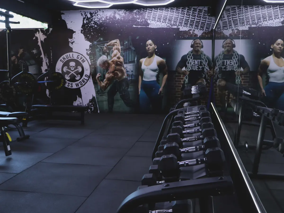 Zona de mancuernas con mural Skull Gym